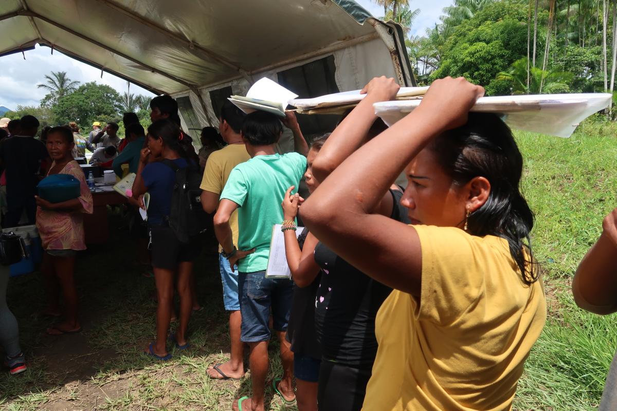 Indígenas aguardam para serem atendidos durante a ação no Parawary carregando pastas de papéis