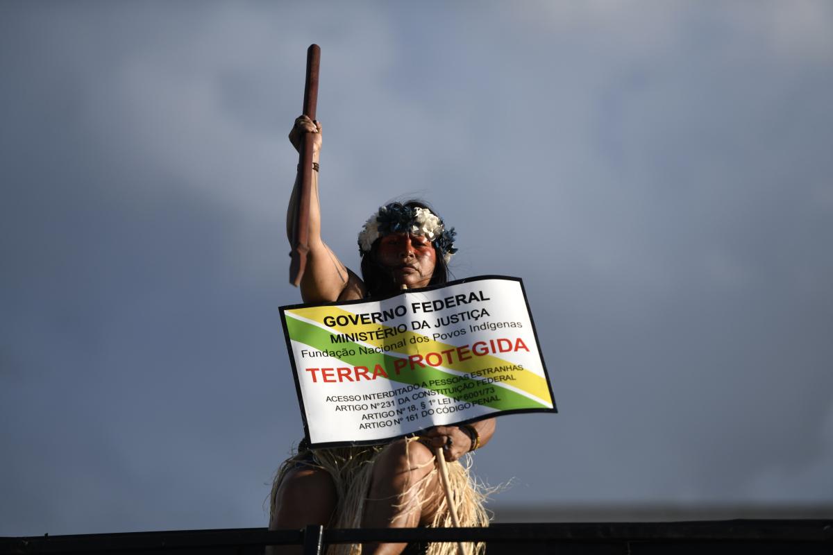 Manifestante com a placa de Terra Protegida do Governo Federal durante o Acampamento Terra Livre 2024