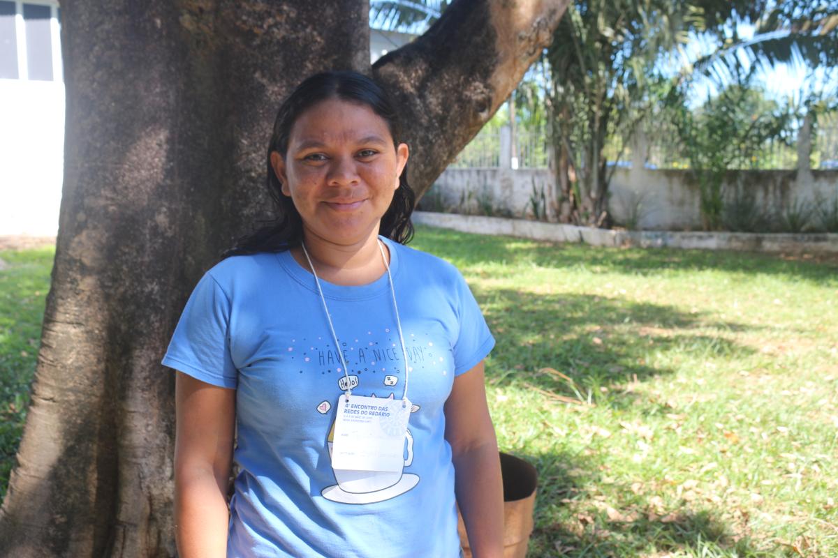 Tjibetjan Arara aparece em frente a uma árvore sorrindo