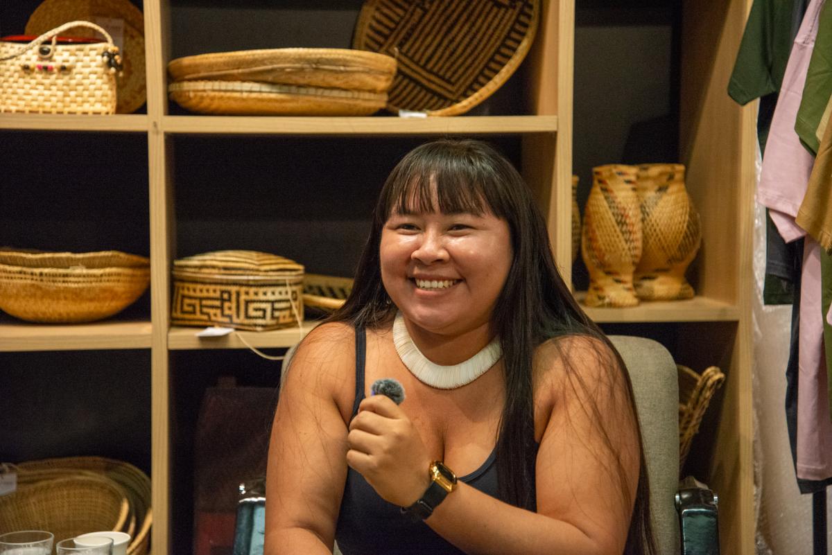 Liderança indígena Yakuwipu Waurá sorri para foto. Na mão dela, tem um microfone pequeno